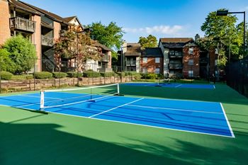 two tennis courts with apartments in the background